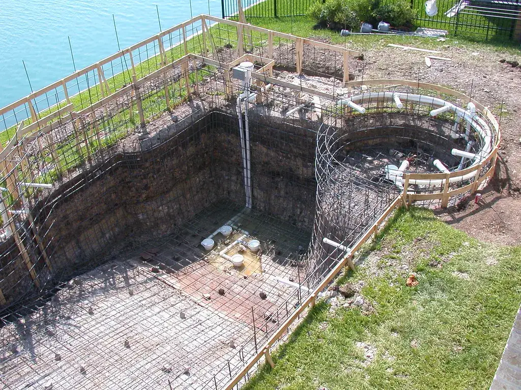 Piscina em construção com ferragens e tubulação instaladas