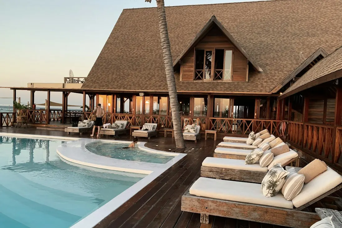 Piscina com prainha e espreguiçadeiras em deck de madeira